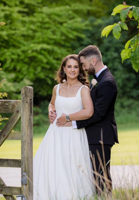 Newleywed couple pose next to fence in paddock at The Rine Hotel Estate in County Clare
